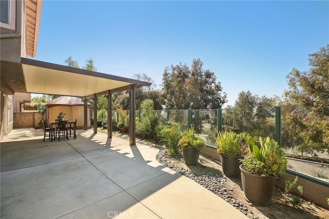 view of patio / terrace with an outbuilding, a storage shed, outdoor dining space, and a fenced backyard