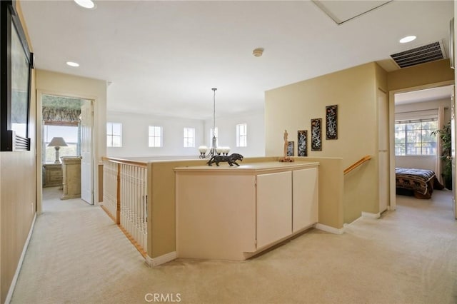 hallway with light colored carpet, a healthy amount of sunlight, visible vents, and an upstairs landing