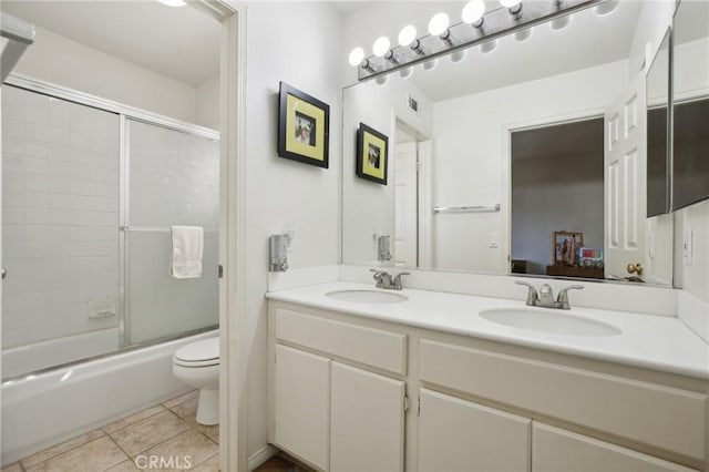 ensuite bathroom with double vanity, a sink, toilet, and tile patterned floors