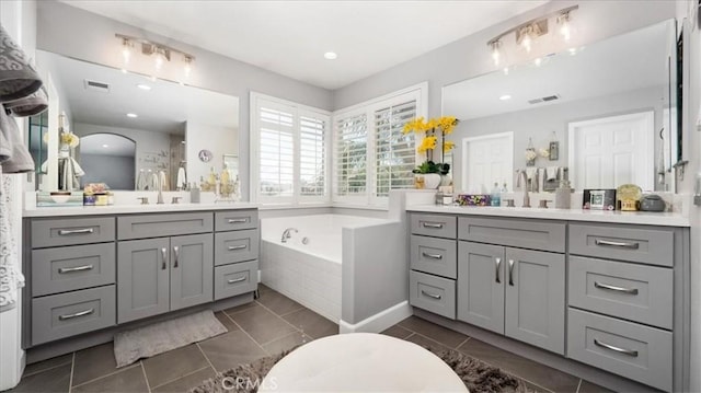 bathroom with visible vents, a garden tub, and a sink