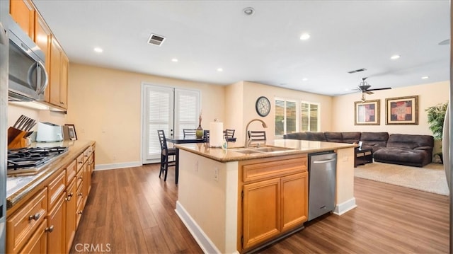 kitchen with visible vents, dark wood-type flooring, a sink, open floor plan, and appliances with stainless steel finishes