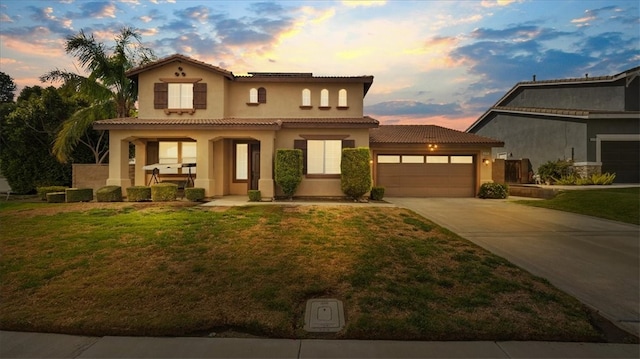 mediterranean / spanish home with stucco siding, an attached garage, a front lawn, and a tile roof