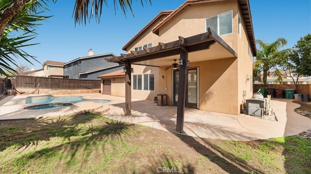 back of property with a patio, an in ground hot tub, a fenced backyard, and stucco siding