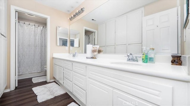 bathroom featuring double vanity, wood finished floors, visible vents, and a sink