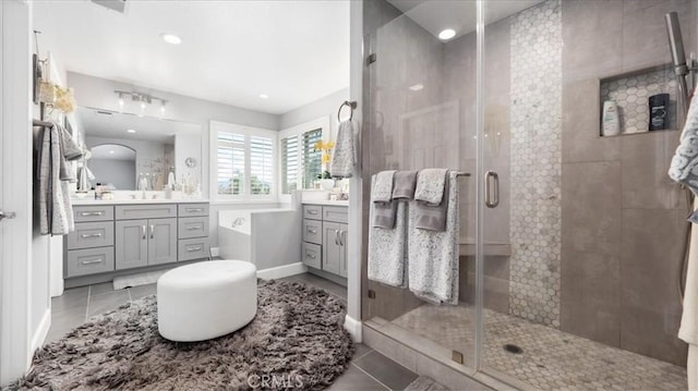 full bathroom featuring tile patterned flooring, a sink, a shower stall, and two vanities