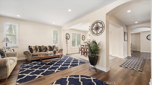 living room featuring recessed lighting, wood finished floors, arched walkways, and baseboards