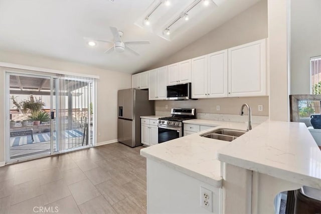 kitchen with lofted ceiling, light stone counters, stainless steel appliances, a peninsula, and a sink