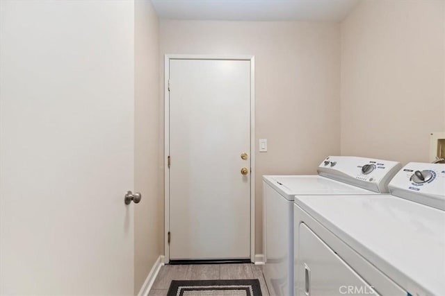 laundry area with laundry area, baseboards, independent washer and dryer, and light wood finished floors