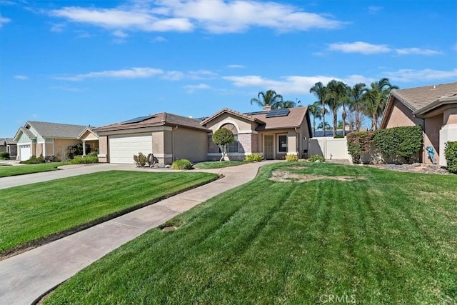 view of front of house with an attached garage, roof mounted solar panels, a front lawn, and stucco siding