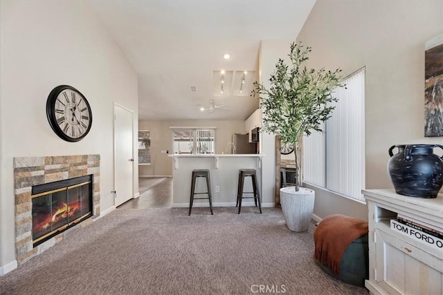 interior space featuring lofted ceiling, a breakfast bar, carpet, stainless steel appliances, and a fireplace