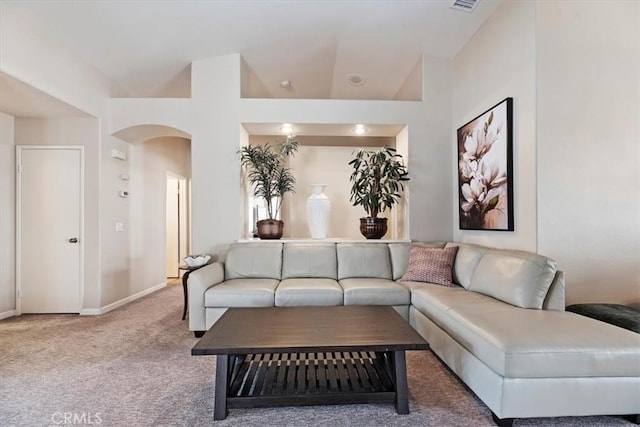 living area featuring carpet, visible vents, arched walkways, and baseboards