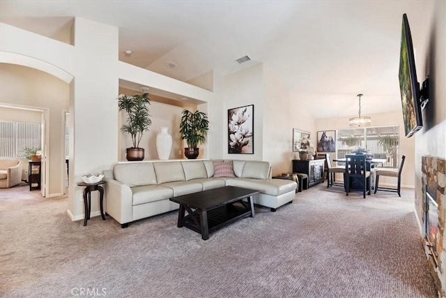 carpeted living area with high vaulted ceiling, arched walkways, visible vents, and baseboards