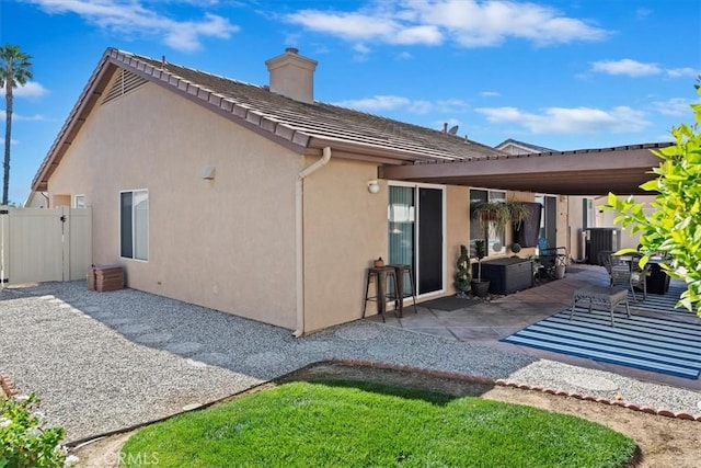 back of property with a patio, a chimney, stucco siding, a gate, and a tiled roof