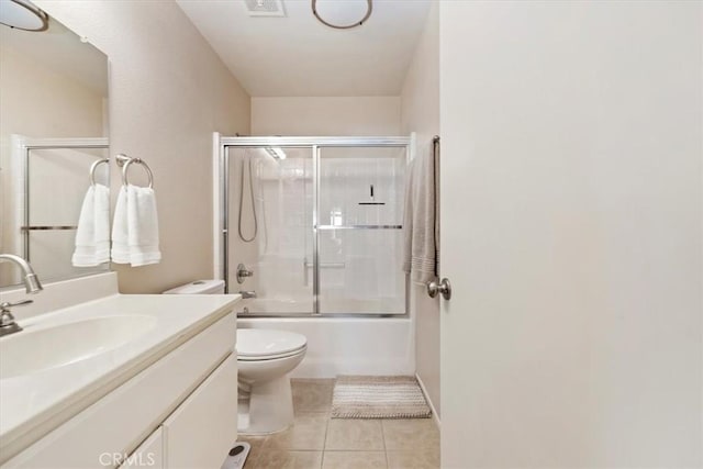 bathroom featuring toilet, combined bath / shower with glass door, tile patterned flooring, and vanity