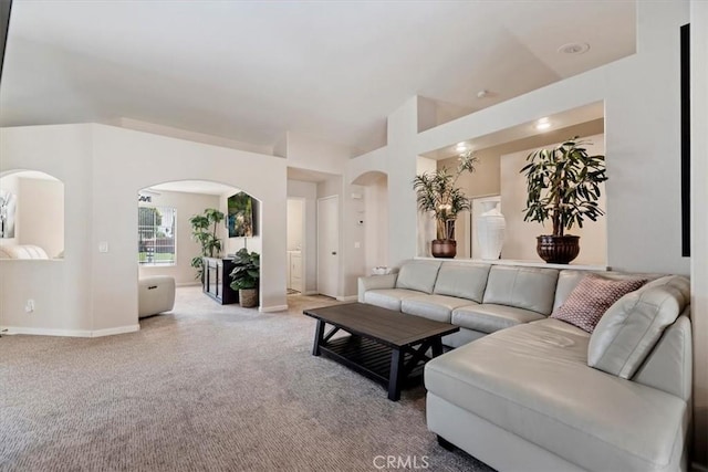 living area with arched walkways, carpet flooring, and baseboards