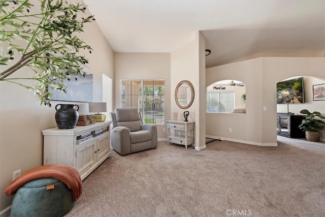 living area with baseboards, a healthy amount of sunlight, and light colored carpet