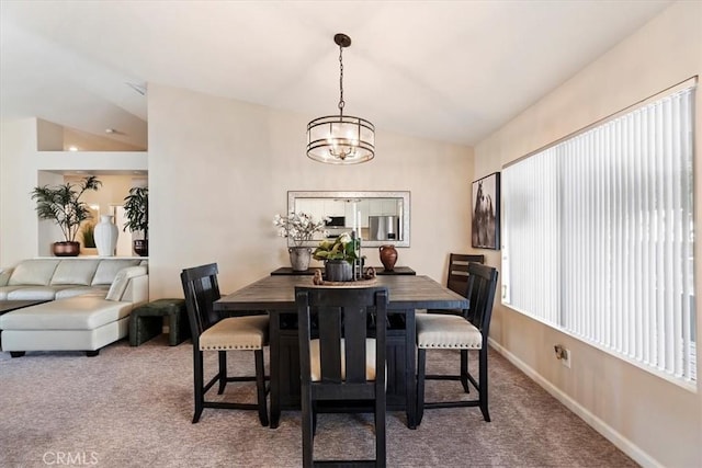 carpeted dining space with lofted ceiling, an inviting chandelier, and baseboards