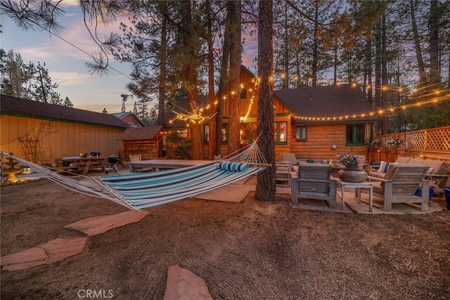 yard at dusk with a patio area, fence, and outdoor lounge area