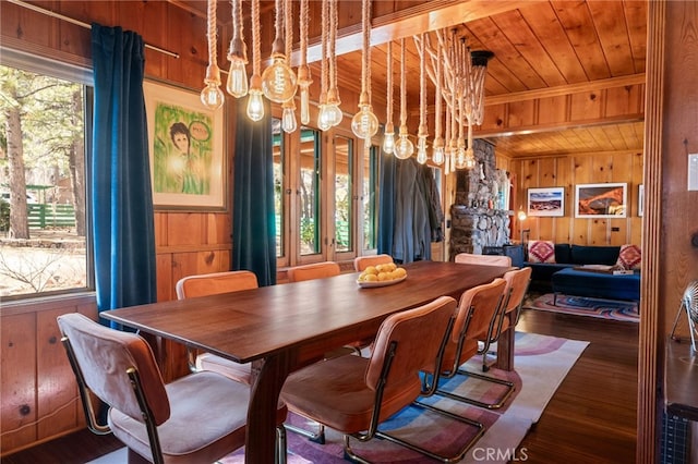 dining space featuring a wealth of natural light, wood ceiling, wooden walls, and an inviting chandelier