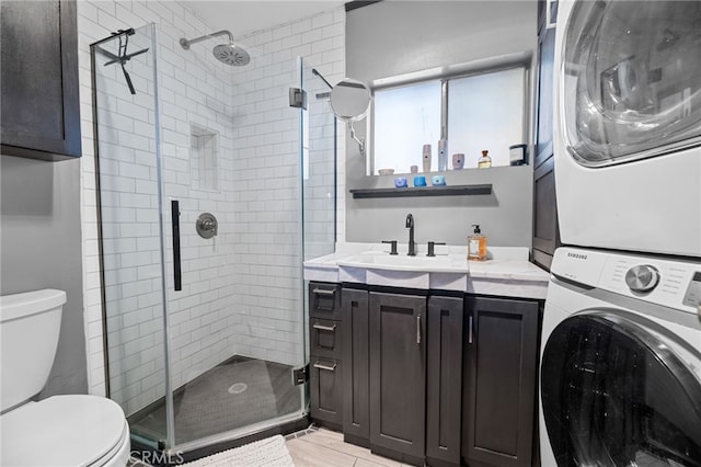 full bath featuring a stall shower, toilet, vanity, and stacked washing maching and dryer