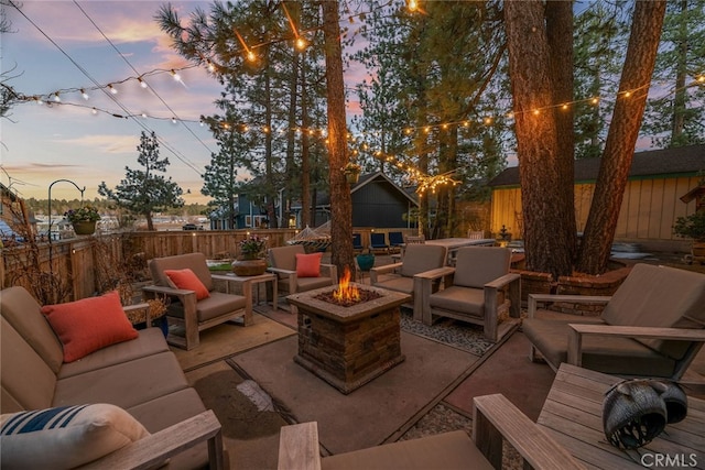 patio terrace at dusk featuring an outdoor living space with a fire pit and a fenced backyard