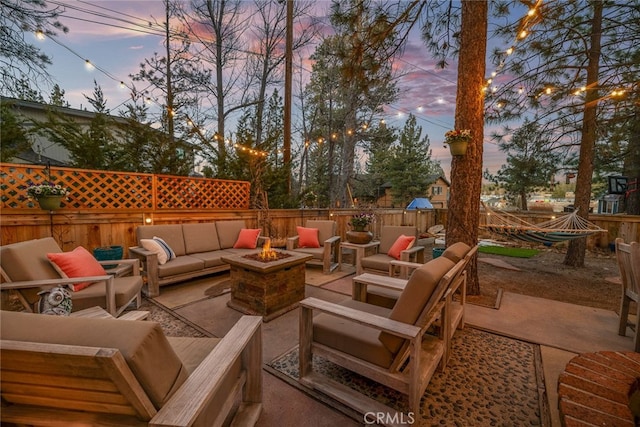 patio terrace at dusk with fence and an outdoor living space with a fire pit