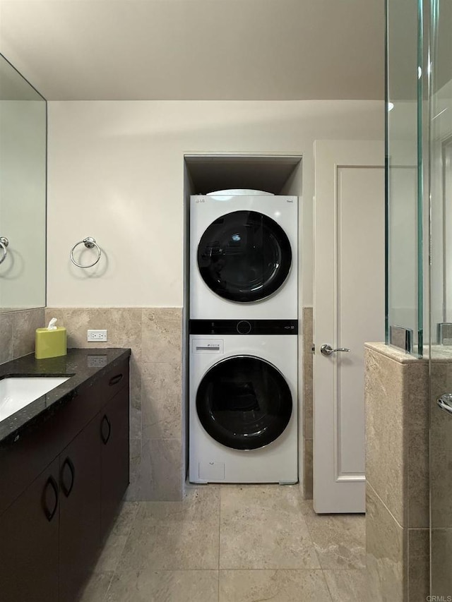 bathroom with wainscoting, vanity, tile walls, and stacked washer / drying machine