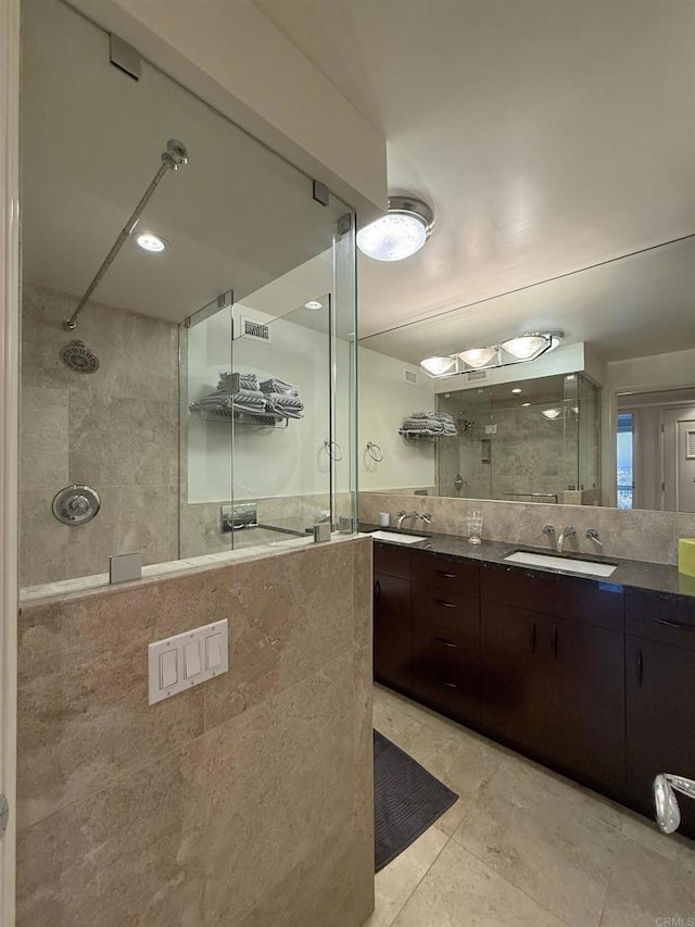 bathroom featuring a sink, tiled shower, and double vanity