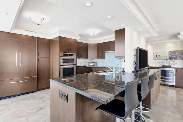 kitchen featuring beverage cooler, visible vents, a breakfast bar, a sink, and double oven