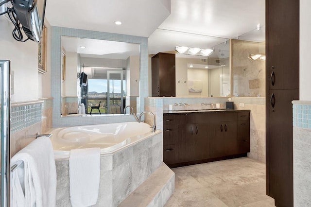 full bath with a garden tub, tile walls, and vanity