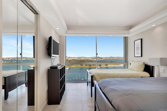 bedroom with a wall of windows, multiple windows, light tile patterned flooring, and a tray ceiling