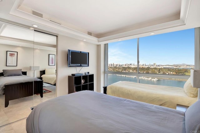 tiled bedroom featuring a tray ceiling, multiple windows, and a closet