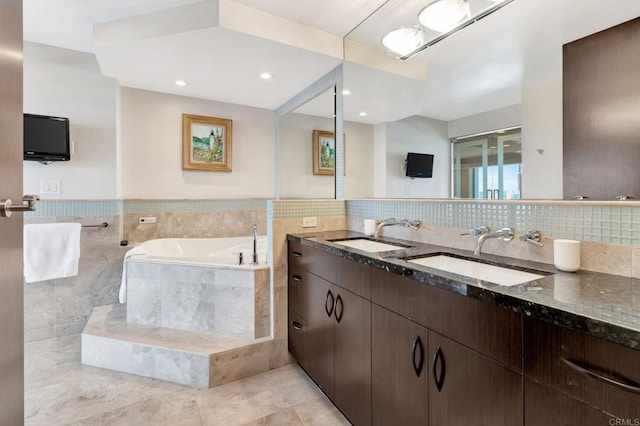 full bathroom featuring a sink, a garden tub, tile walls, and double vanity