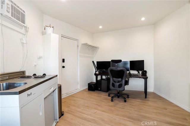 office space featuring baseboards, a wall unit AC, recessed lighting, light wood-style flooring, and a sink