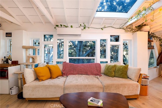 living area featuring a healthy amount of sunlight, vaulted ceiling with beams, wood finished floors, and a wall mounted AC