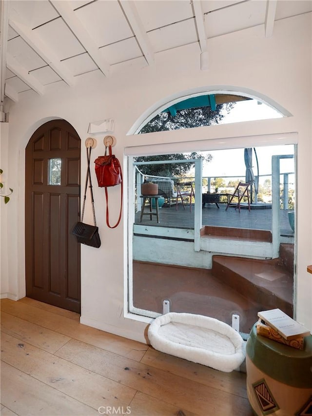 entryway featuring beamed ceiling, arched walkways, wood ceiling, and light wood finished floors