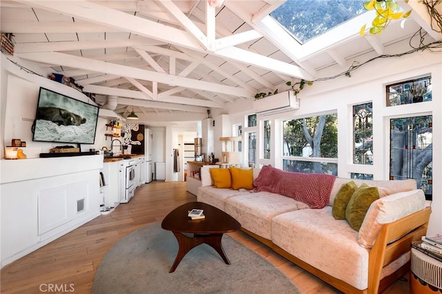 living room with vaulted ceiling with skylight, light wood-style flooring, and a wall mounted air conditioner