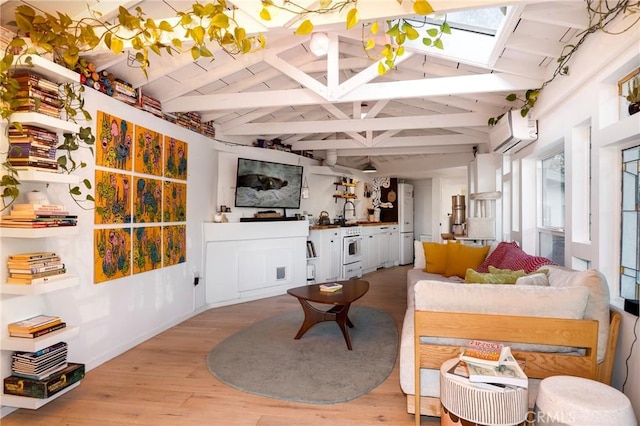 living area featuring an AC wall unit, vaulted ceiling with skylight, and light wood-style floors