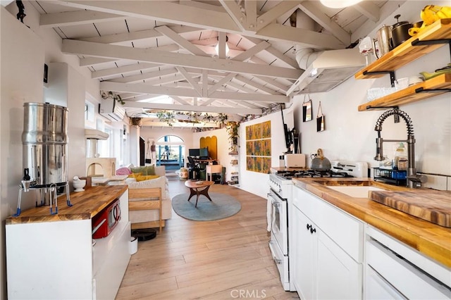 kitchen with light wood finished floors, wooden counters, vaulted ceiling with beams, white gas range oven, and white cabinetry