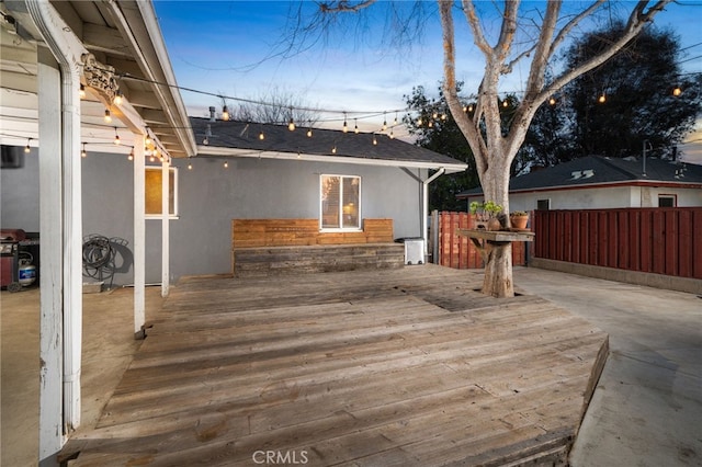 deck at dusk featuring fence