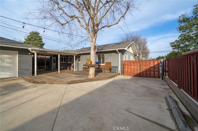 back of property with a deck, a patio, fence, and stucco siding