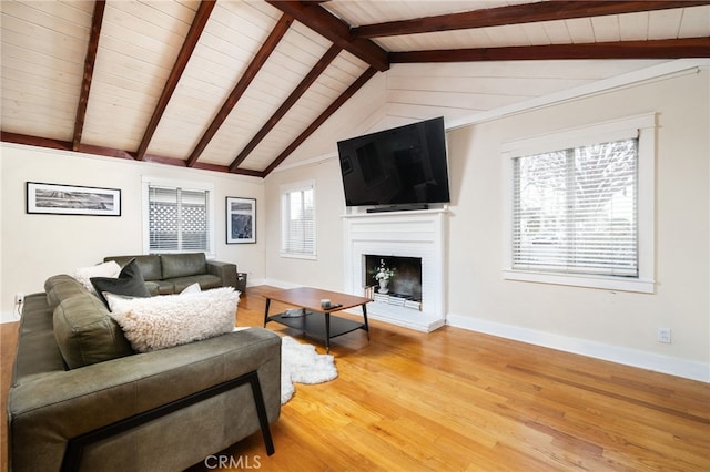 living room featuring vaulted ceiling with beams, a fireplace, wood finished floors, and baseboards