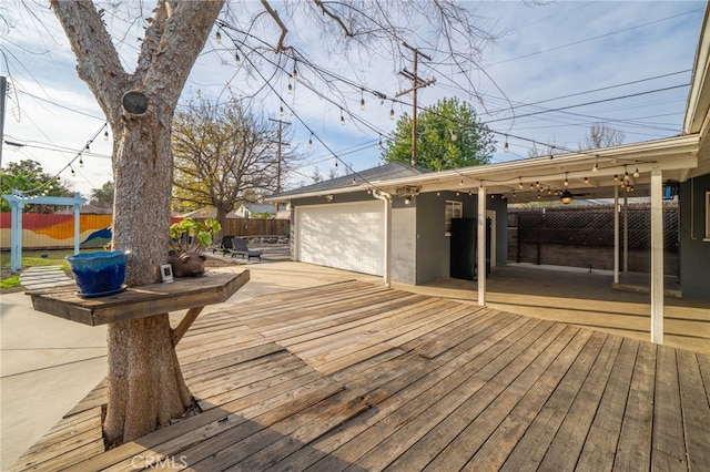 wooden terrace featuring concrete driveway and fence