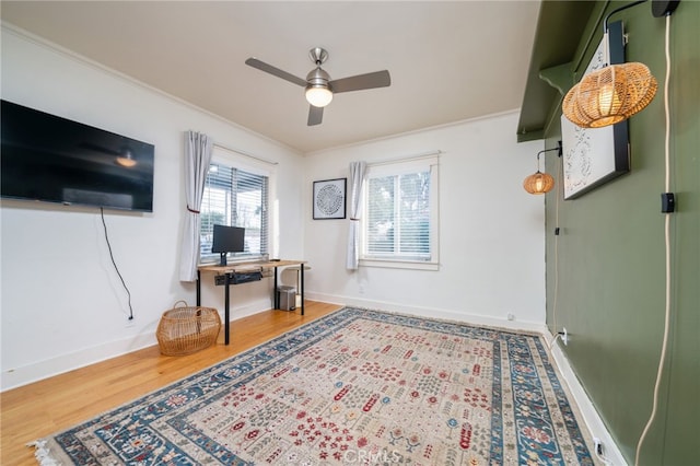 office space featuring ornamental molding, a ceiling fan, baseboards, and wood finished floors