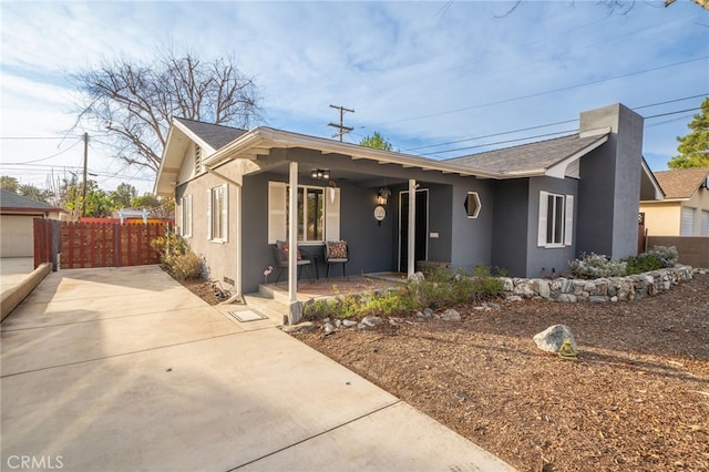 view of front of home with a porch, fence, and stucco siding