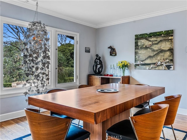 dining space featuring light wood finished floors, baseboards, and crown molding