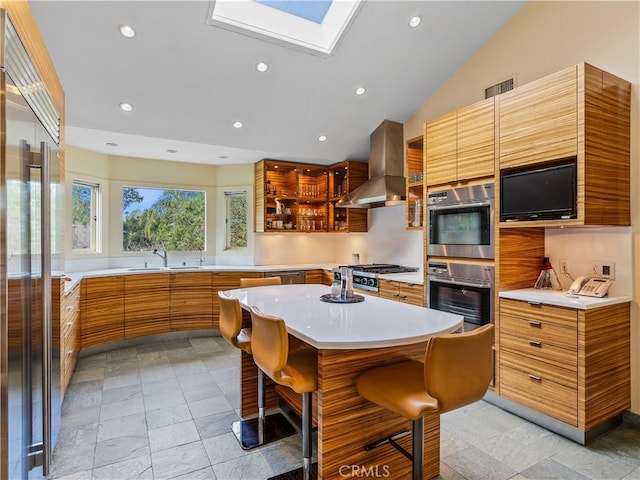 kitchen with extractor fan, a kitchen island, light countertops, appliances with stainless steel finishes, and a kitchen bar