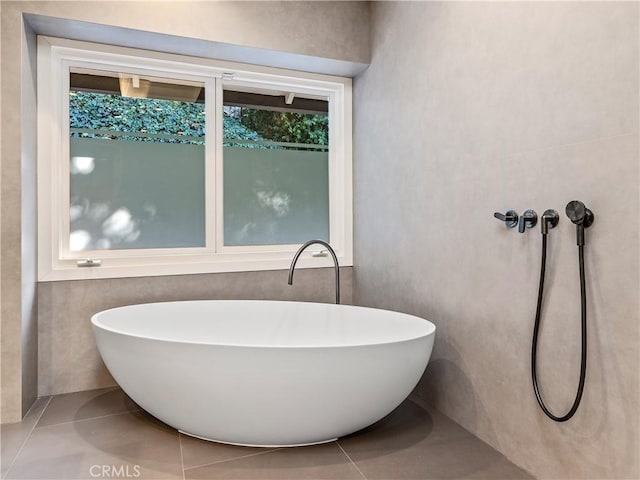 full bath with a healthy amount of sunlight, a soaking tub, and tile patterned flooring