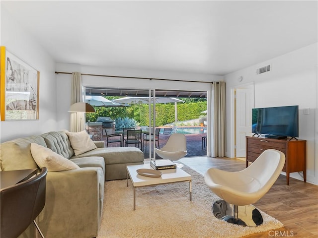 living room with a healthy amount of sunlight, visible vents, and light wood finished floors