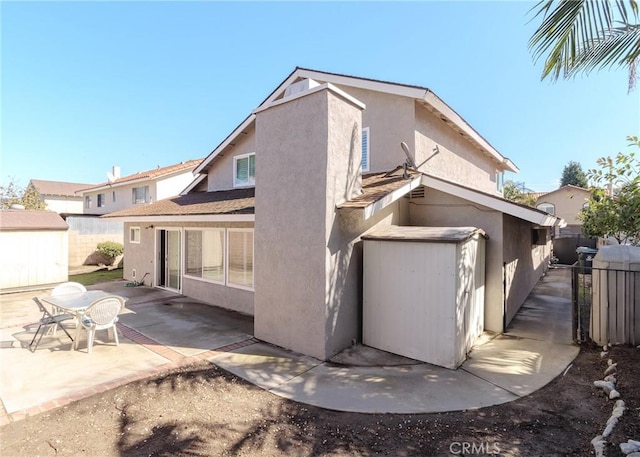 back of property with a patio area, a shed, an outdoor structure, and stucco siding